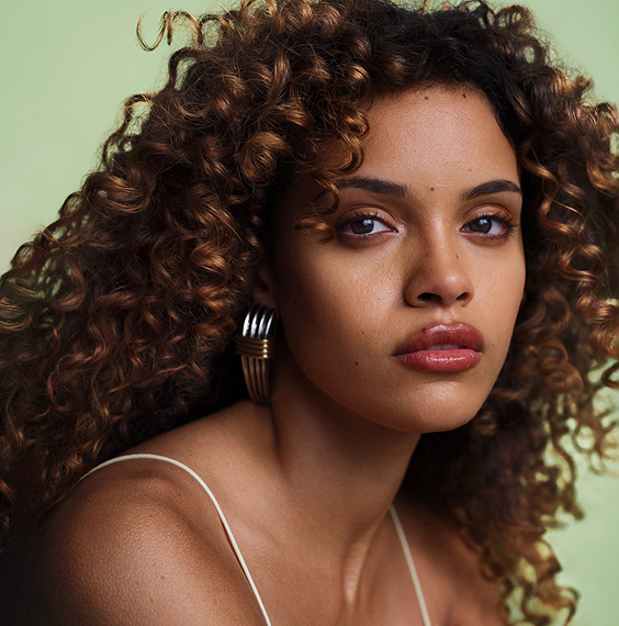 Model with curly hair against green background