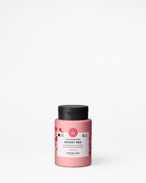 Pink hair color product jar with black lid on a white background
