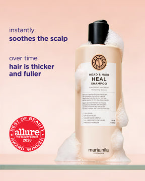 Maria Nila Heal Shampoo bottle with white foam, set against a soft peach background with promotional text and an Allure award badge.