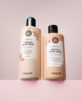 Maria Nila Exclusively for Liberty Head & Hair Heal shampoo and conditioner bottles on a pink background